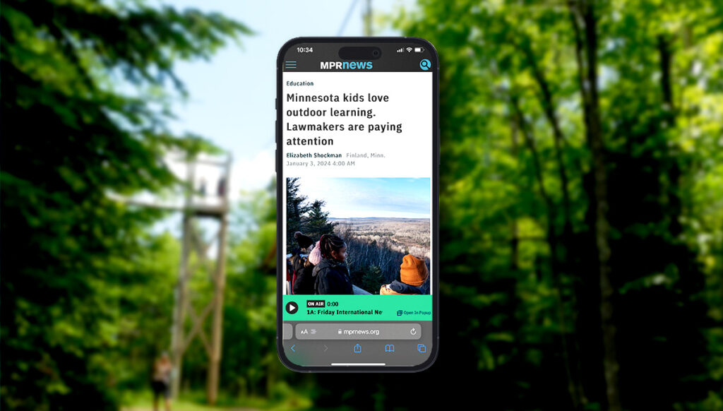 Cell phone screen displaying a news article titled 'Minnesota Kids Love Outdoor Learning: Lawmakers Are Paying Attention,' highlighting growing interest in outdoor education among lawmakers in Minnesota
